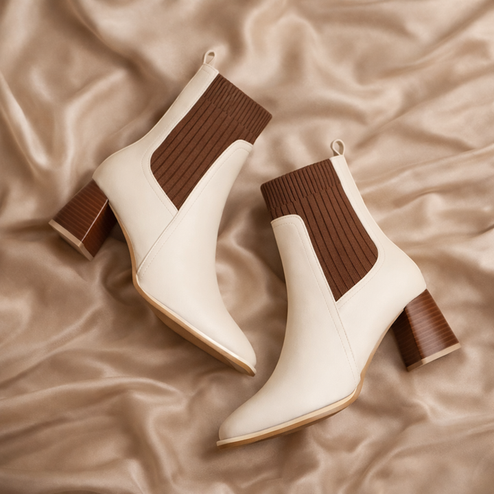 Ivory leather ankle boots with ribbed knit panel and block heel from the Dylan Archer women’s footwear collection, place on a silk fabric. defined by an elegant chic style and a refined, modern silhouette.